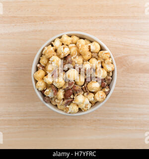 Top view of a bowl filled with gourmet popcorn, almonds and pecans on a wood table. Stock Photo