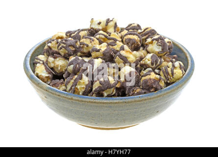 A serving of fudge drizzled popcorn in an old stoneware bowl isolated on a white background. Stock Photo