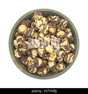 Top view of a serving of fudge drizzled popcorn in an old stoneware bowl on a white background. Stock Photo