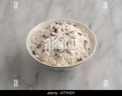 Imitation blueberry muffin mix in a white bowl on a gray marble cutting board. Stock Photo