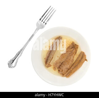 Top view of skinless mackerel fillets in olive oil on a plate with a fork to the side. Stock Photo