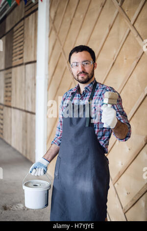 young painter man with tin of painting and brush showing thumbs up Stock Photo