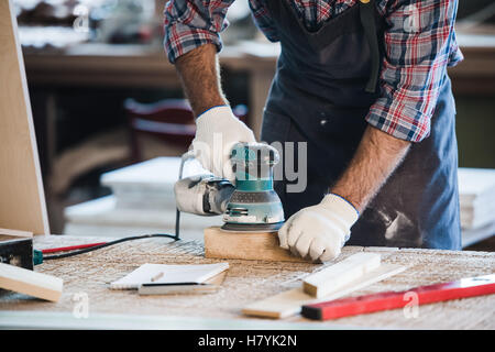 Worker grinds the wood of angular grinding machine Stock Photo