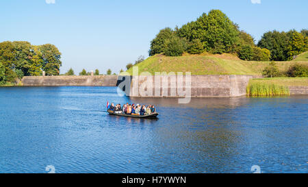 People in tourist boat on moat and bastion Oud Molen in fortified town of Naarden, North Holland, Netherlands Stock Photo