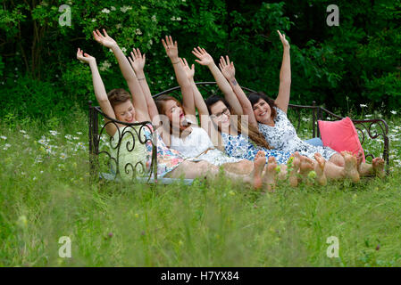 Young women sitting on sofa, posing, playful, meadow, Upper Bavaria, Bavaria, Germany Stock Photo