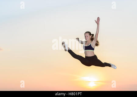 The young girl engaged in artistic gymnastics at sunset background Stock Photo