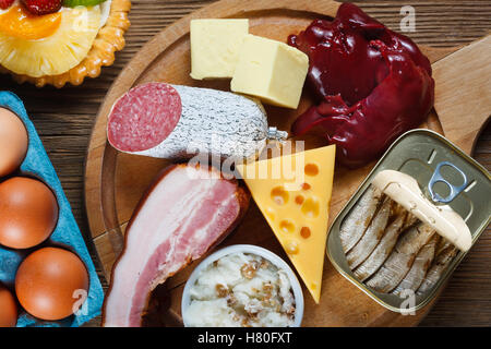 Foods rich in cholesterol as eggs, liver, yellow cheese, butter, bacon, lard with onion, sardines in oil and sweet dessert - cup Stock Photo