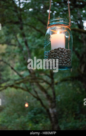 Mason jars with candles hanging from the trees. Stock Photo