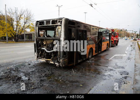 Burnt public traffic bus is seen on the street after caught in fire during travel and extinguished by firefighters. Stock Photo