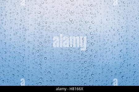 Background of close focus on graduated blue tone from soft to dark of drop of rain water on window glass after raining on rainy Stock Photo