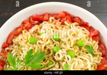 Prepared noodles with tomato and peas in a bowl Stock Photo