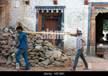 Men carry rocks for the restoration of Trashigang Dzong after earthquake damage. Stock Photo