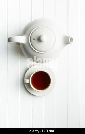 A cup of black tea and teapot on white table. Top view. Stock Photo