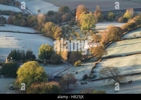 House and farmland in the valley of Downham Hill from Uley Bury on a cold frosty autumn morning just after sunrise. Gloucestershire, England Stock Photo