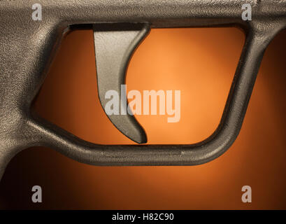 Trigger on an assault rifle with a brown background Stock Photo