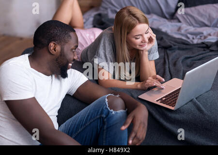 International couple using laptop in bed Stock Photo