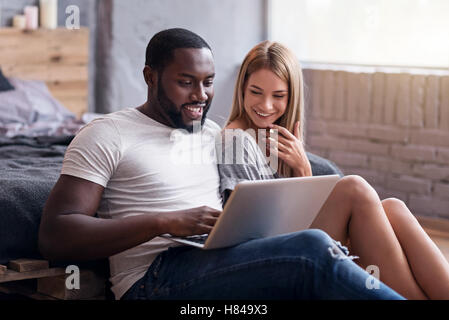 Happy couple using laptop in bedroom together Stock Photo