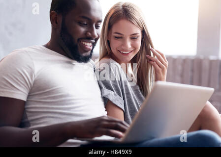 Laughing couple using laptop together Stock Photo