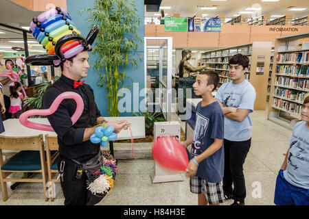 Miami Florida,Hialeah,JFK Library,Health & Literacy Fair,interior inside,Hispanic man men male,balloon artist,twister,modeling,hat,teen teens teenager Stock Photo