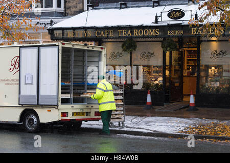 Ilkley, West Yorkshire, UK. 9th November 2016. A fresh morning delivery has arrived by van and loaves of bread are being unloaded on trays by a man, before being taken into Bettys Cafe Tea Rooms during Ilkley's first snowfall of 2016. Credit:  Ian Lamond/Alamy Live News Stock Photo