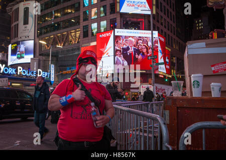 New York, NY, USA - 9th November 2016. 3:13 AM: a Trump supporter (foreground) gestures while looking at the photographer in Times Square and while Trump is shown on a screen behind him doing the same gesture. Photo: Alessandro Vecchi dpa