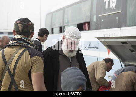 Mosul, Nineveh, Iraq. 10th Nov, 2016. 10/11/2016. Mosul, Iraq. Iraqi men, holding bags containing their possessions, wait in line as the prepare to board a bus that will evacuate them from Mosul's Gogjali District. The bus, provided by the Iraqi Army, will take them away from the fighting in the city to the safety of a refugee camp in Iraqi-Kurdistan. Credit:  ZUMA Press, Inc./Alamy Live News Stock Photo