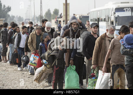 Mosul, Nineveh, Iraq. 10th Nov, 2016. 10/11/2016. Mosul, Iraq. Iraqi men, holding bags containing their possessions, wait in line as the prepare to board a bus that will evacuate them from Mosul's Gogjali District. The bus, provided by the Iraqi Army, will take them away from the fighting in the city to the safety of a refugee camp in Iraqi-Kurdistan. Credit:  ZUMA Press, Inc./Alamy Live News Stock Photo