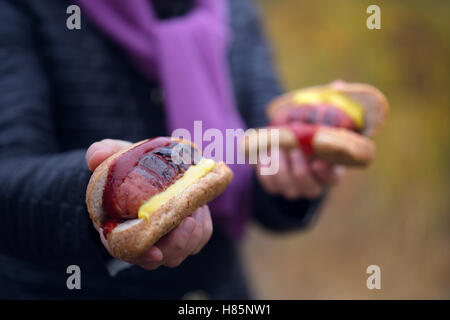 Woman hands holding barbecue grilled hot dog with yellow mustard and  ketchup Stock Photo