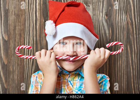 Little boy in a New Year's red cap with two Christmas candy canes Stock Photo