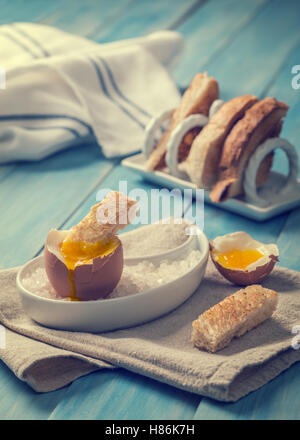 Buttered toast being dipped into soft boiled egg - focus on dipped toast slice Stock Photo