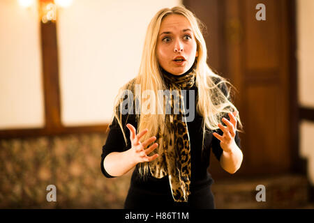A Young woman actor wearing plain black costumes performing solo monologue extracts from Shakespeare's plays and poetry in a small scale theatre space above a pub in Aberystwyth Wales UK Stock Photo