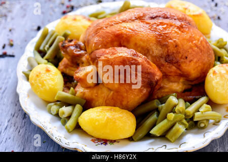 closeup of a roast turkey served with potatoes and french beans on a round ceramic tray, placed on a rustic wooden table Stock Photo