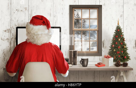 Cold winter time at Santa Claus home. Santa Claus work online on his computer. Gifts, Christmas tree and decorations on table. S Stock Photo