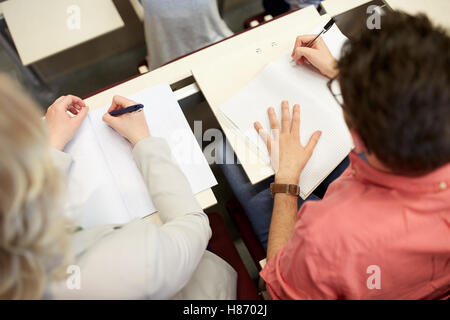 students writing to notebooks at exam or lecture Stock Photo
