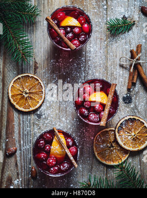 Hot spicy mulled wine with cranberries, cinnamon and orange in glasses on wooden table. Top view Stock Photo