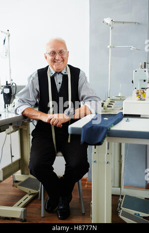 Smiling tailor sitting in workshop Stock Photo