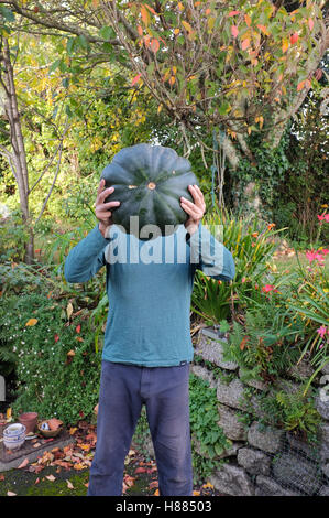 A man holds up a large squash that he has grown in his garden in Cornwall, UK Stock Photo