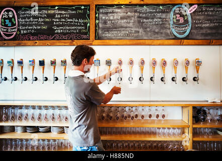 Man pulling a glass of beer from a tab in a brewery. Stock Photo