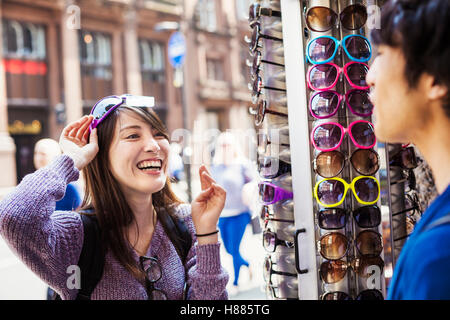 A Japanese woman trying on sunglasses in London, a summer tourist visitor. Stock Photo