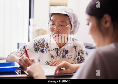 A mature woman at a desk in the office of a fast food unit and noodle production factory. Stock Photo