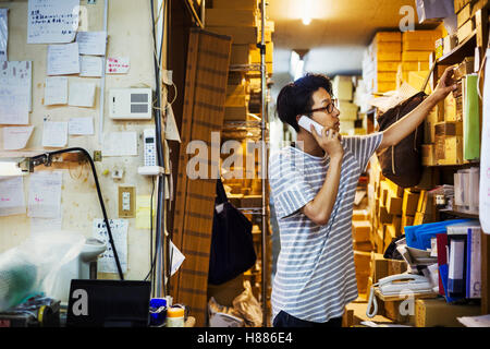 A man at work in a glass maker's studio workshop on the phone. Stock Photo
