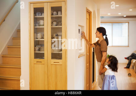 Family home. A woman adjusting the thermostat on a wall in the house. Stock Photo