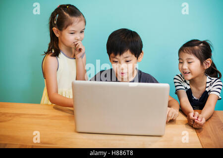 A group of children in school, three children sharing a laptop computer. Stock Photo