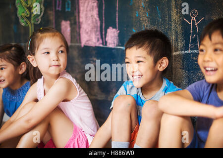 A group of children in school. Boys and girls sitting on the floor. Stock Photo