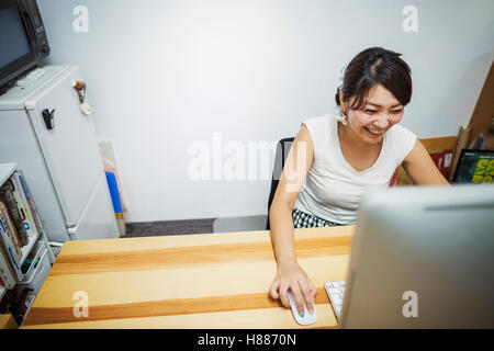 Design Studio. A woman working at a desk using a mouse and computer. Stock Photo