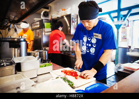 The ramen noodle shop. Three chefs working in a small kitchen, staff preparing food Stock Photo