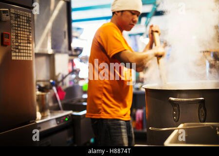The ramen noodle shop. Staff preparing food in a steam filled kitchen. Stock Photo
