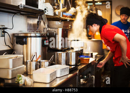 The ramen noodle shop.  Staff preparing food in a tiny kitchen Stock Photo