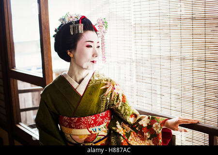 A woman dressed in the traditional geisha style, wearing a kimono and obi Stock Photo