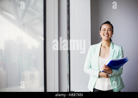 A business woman in the office holding a folder and smiling. Stock Photo